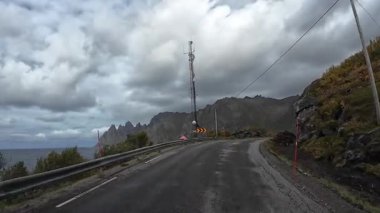 Norveç 'in kuzeyindeki dolambaçlı bir fiyort yolunda bulutlu bir sonbahar gününde çekilen görüntüler.