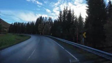 Norveç 'in sonbahar kırsalında ıslak asfalt bir yolda resimli bir karavan yolculuğu