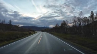 Norveç 'in kuzeyindeki bir dağ manzarasından geçen dolambaçlı bir yolda bir karavanı süren bir bakış açısı