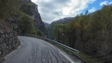 Norveç fiyordunun yanındaki virajlı yolda giden eğlence amaçlı bir araçtan bakış açısı