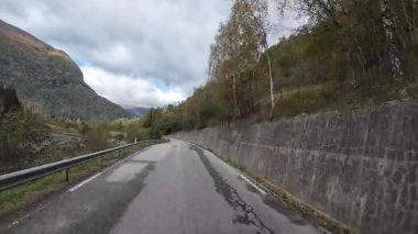Norveç 'in dağları ve sonbahar doğasıyla çevrili manzaralı bir yolda karavanın bakış açısı