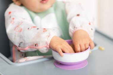 Bebek elleri, kendini beslemeyi öğrenirken bir kaseden yeni yemek dokularını keşfediyor.