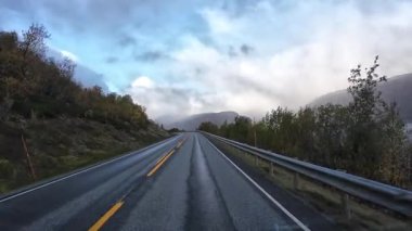 Bakış açısı, güneşli bir günde Norveç 'te bir sahil yolunda bir karavan sürerken çekilmiş.