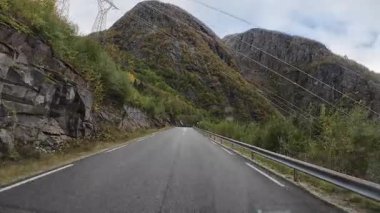 Güneşli bir günde Lofoten Adaları 'nın güzel manzarası olan bir dağ yolunda karavanla yolculuk yapmak.