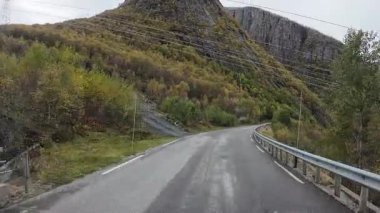 Güneşli bir günde Lofoten Adaları 'nın güzel manzarası olan bir dağ yolunda karavanla yolculuk yapmak.