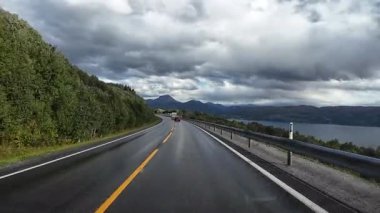 Lofoten Adaları, Norveç; 11 Eylül 2024: Lofoten 'de dağlarla ve fiyortlarla çarpıcı bir sahil yolu boyunca araba sürerken çekilen görüntüler