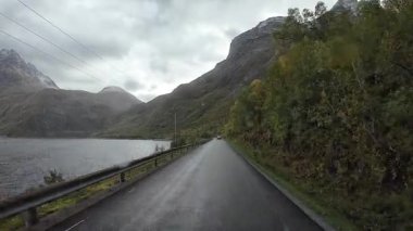 Lofoten Adaları, Norveç; 11 Eylül 2024: Lofoten 'de dağlarla ve fiyortlarla çarpıcı bir sahil yolu boyunca araba sürerken çekilen görüntüler