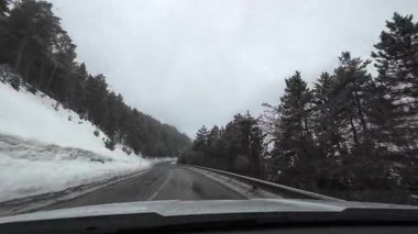 İspanya 'nın La Molina şehrinde kış boyunca virajlı ve karlı bir yolda giden bir arabadan bakış açısı