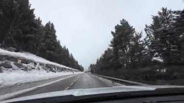 İspanya 'nın La Molina şehrinde kış boyunca virajlı ve karlı bir yolda giden bir arabadan bakış açısı