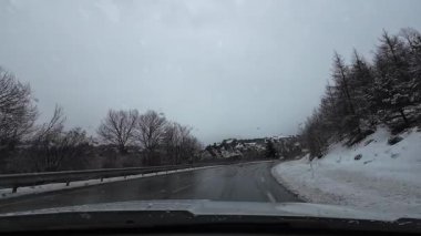 İspanya 'nın La Molina şehrinde kış boyunca virajlı ve karlı bir yolda giden bir arabadan bakış açısı