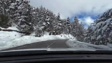 İspanya 'nın La Molina şehrinde kış boyunca virajlı ve karlı bir yolda giden bir arabadan bakış açısı