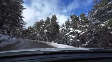 İspanya 'nın La Molina şehrinde kış boyunca virajlı ve karlı bir yolda giden bir arabadan bakış açısı
