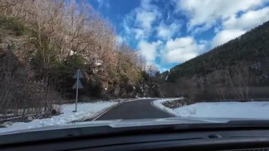 İspanya 'nın La Molina şehrinde kış boyunca virajlı ve karlı bir yolda giden bir arabadan bakış açısı
