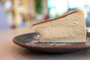 Tahta masadaki seramik tabakta dilimlenmiş peynirli kek..