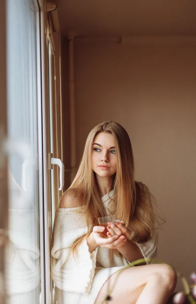 Mulher loira bonita bebendo chá pela manhã sentado à janela — Fotografia de Stock