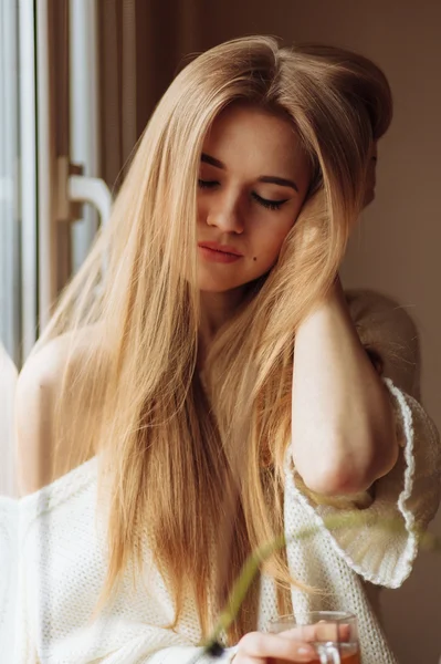 Beautiful blond woman drinking tea in the morning sitting by the window — Stock Photo, Image