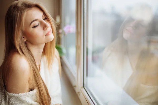 Cam kenarında oturan sabah çay içme güzel sarışın kadın