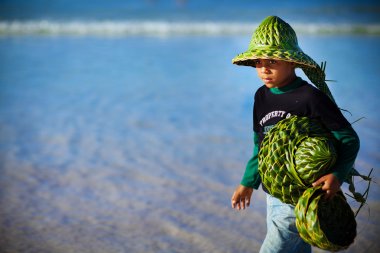 Young boy sells hats made of palm leaves, Dominican Republic clipart