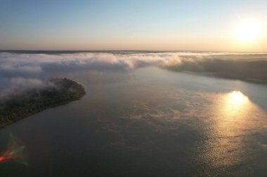 Gölde sis var. Altın güneş ışığı yazın su yüzeyinde hareket eden portakal sisi oluşturur. Orman arka planı ve güzel barışçıl yansımalar.