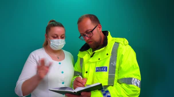 フレンドリーな警官は笑顔の女性と話す 女性医師や男性警察官との会話 背景に隔離された反射的な制服で英国の警察官 — ストック動画