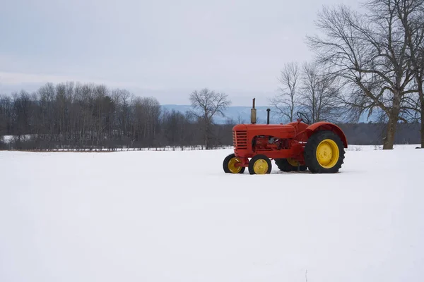 A red tractor in a snow filled farmers field