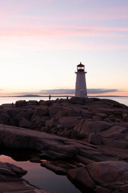 Alacakaranlıkta kayalık bir uçurumun kıyısında bir deniz evi.