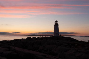 Alacakaranlıkta kayalık bir uçurumun kıyısında bir deniz evi.