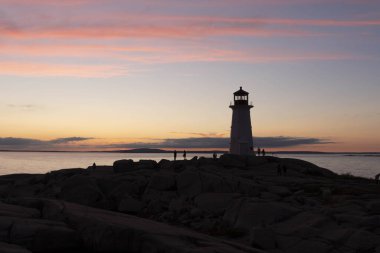 Alacakaranlıkta kayalık bir uçurumun kıyısında bir deniz evi.