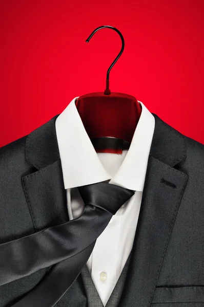 Mens dark grey suit closeup on clothes hanger on red background. Stock Image