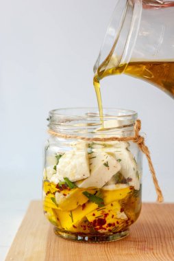 Şeffaf cam kavanozda zeytinyağlı Gürcü Imeretian peyniri dilimleri.