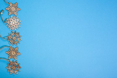 Mavi arka planda tahta kar taneleri çizgisi. Kış ya da Noel konsepti, düz konum, üst görünüm, kopyalama alanı