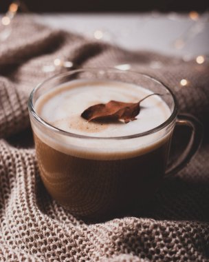 Amerikan kahvesi şeffaf bardakta örgü yüzeyinde sarı ışıklarla. Sonbahar havası