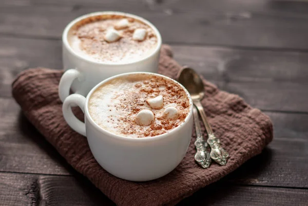 Två Vita Koppar Cappuccino Med Marshmallows Och Skedar Träbord — Stockfoto
