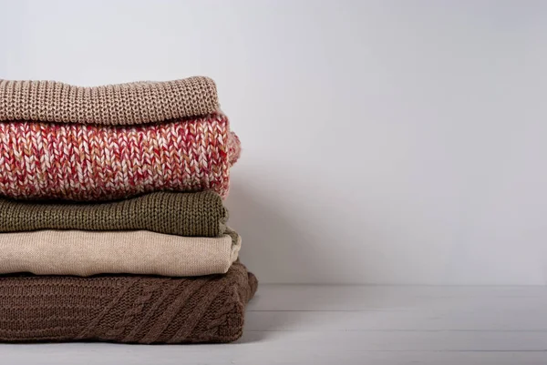 Beyaz ahşap arka planda katlanmış renkli süveter yığını