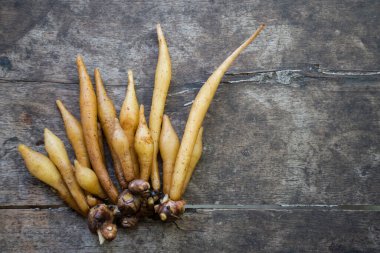Kaempferia eski dokularla ahşap bir masanın üzerine konur. Metin için kopyalama alanı ile. Kaempferia Tayland yemeği, anti-Covid-19 özütü. Üstten bir fotoğraf çek. Doğal bir tıbbi bitki konsepti. 
