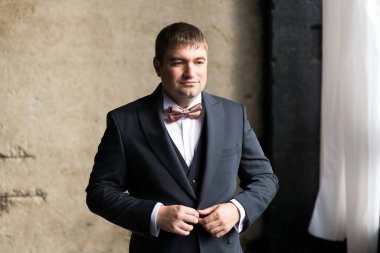 Bir adam iş elbisesinin düğmelerini bağlar.