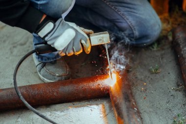 Elektrikli kaynakçı metal bir boruyu kaynaklıyor.