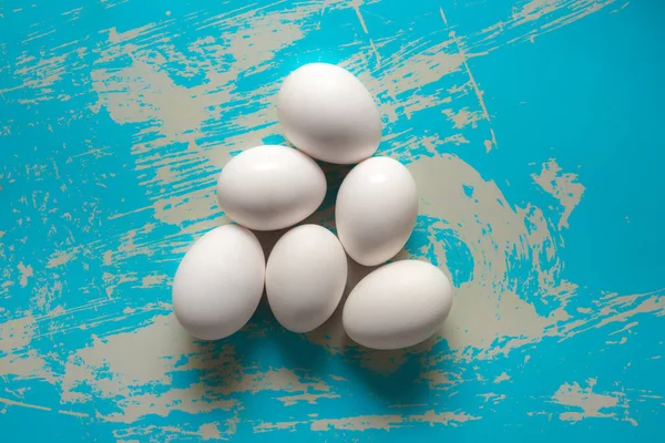 Chicken eggs lie on a vintage blue background with scratches.