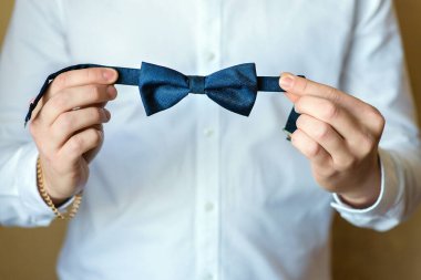 Beyaz gömlekli bir adam papyon tutuyor.