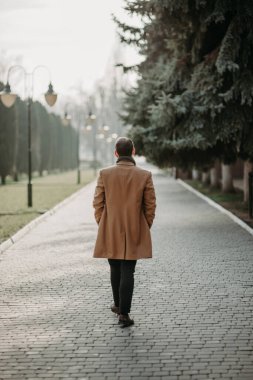 Bir Avrupa şehrinin uzun bir caddesi boyunca yürüyen bir adam.