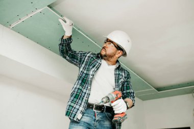 Miğferli bir inşaatçı alçıdan bir tavan yapar.