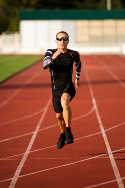 Koşucu stadyumdaki pistte koşuyor.
