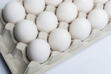 Karton bir kutuda beyaz tavuk yumurtası. Kağıt tepside yumurtalar.