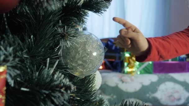 Çocuk süslenmiş Noel ağacında bir Noel mücevheri açıyor. — Stok video