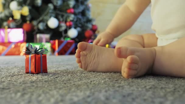 Bambino raccoglie un regalo vicino all'albero di Natale decorato — Video Stock