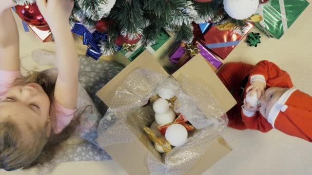 Hermana y su hermano pequeño decoran el árbol de Navidad — Vídeos de Stock