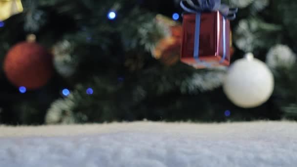 Jultomten sätter en gåva nära den dekorerade julgranen. — Stockvideo