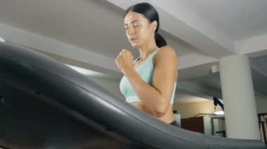 Genç atletik kadın spor salonunda koşu bandında koşuyor..