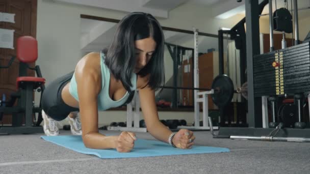 Młoda kobieta w odzieży sportowej robi ćwiczenia deski — Wideo stockowe