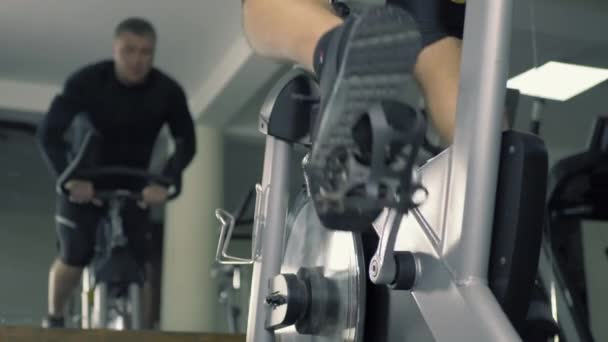 Atletický muž trénuje na stacionárním tréninkovém kole — Stock video